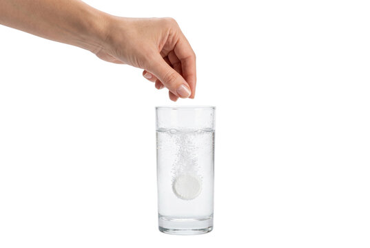 Hand dropping effervescent soluble tablet into glass of water