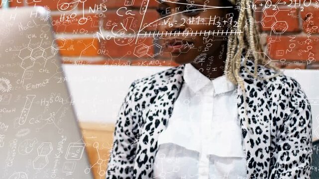 Camera pulling back woman at laptop science formulas overlaying brick wall leaning, typing solving