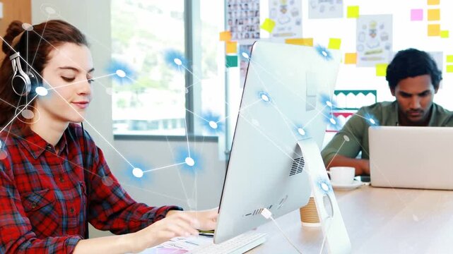 Woman typing in creative office causing network nodes to expand across monitor showing design links