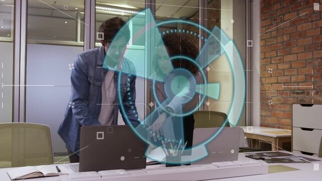 Female designer pointing at laptop and starting blue HUD while man leaning in checking design mocks