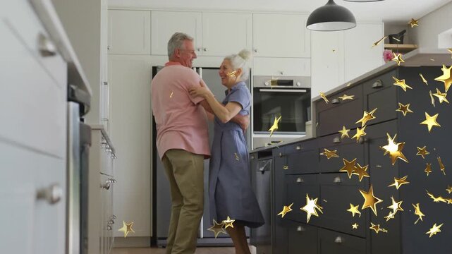 Couple hugging, swaying in home kitchen by fridge and oven, smile sparking gold stars covering pair