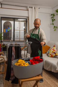 Hispanic man placing sweater on hanger preparing laundry to dry