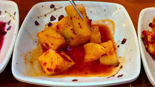 Korean traditional food Radish Kimchi - Kkakdugi. Pick up KKAKDUGI with chipsticks. Sliced radish kimchi