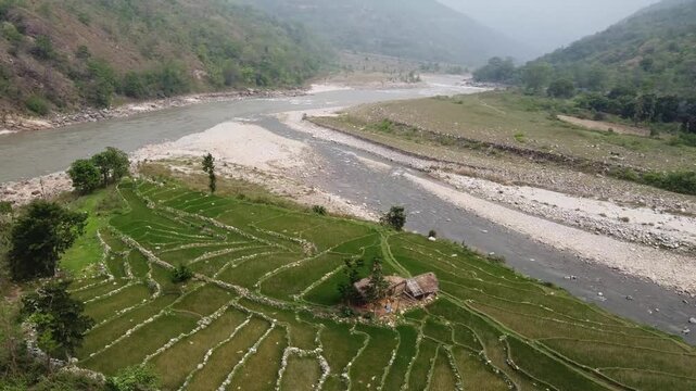 Beautiful aerial landscape showing green terraced farmland beside the flowing Arun and Pikhua Rikhuwa rivers. The peaceful mountain valley features winding waterways, rocky riverbanks, and a small rur