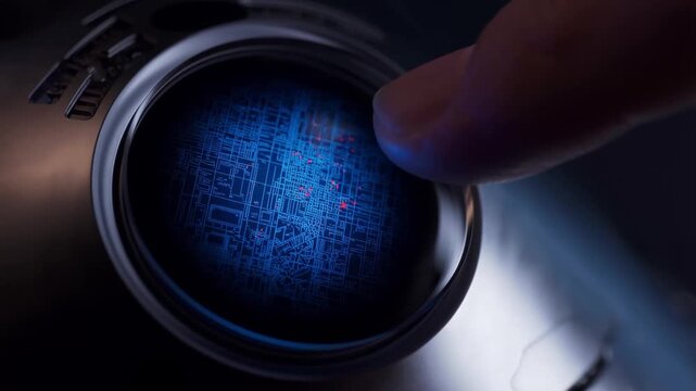 A finger touches a glowing blue orb on a metallic device, activating a complex circuit pattern with small red light particles in a futuristic, high-tech setting.