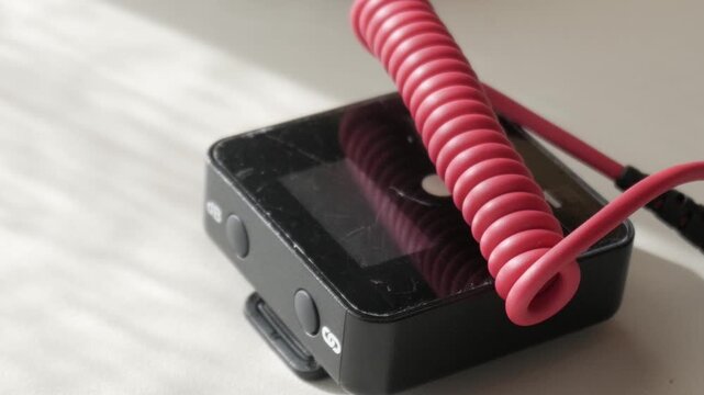 Close-up of a lavalier radio mic on a table with coiled cable