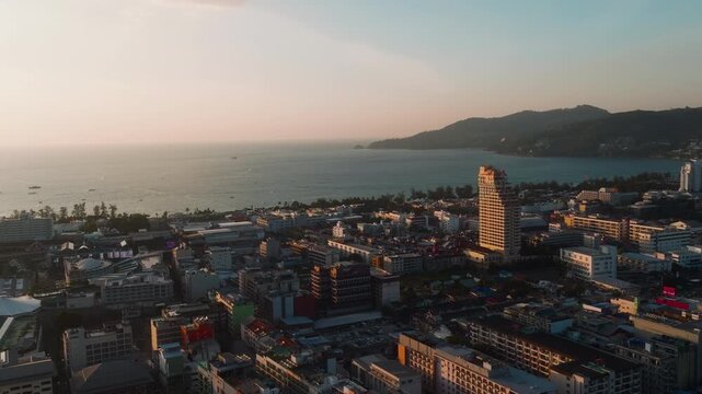 Orbiting drone shot over Patong city and bay at sunrise in Phuket
