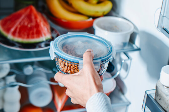 a man places a container of lentils in the fridge