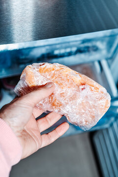 a man grips frozen chicken from the freezer