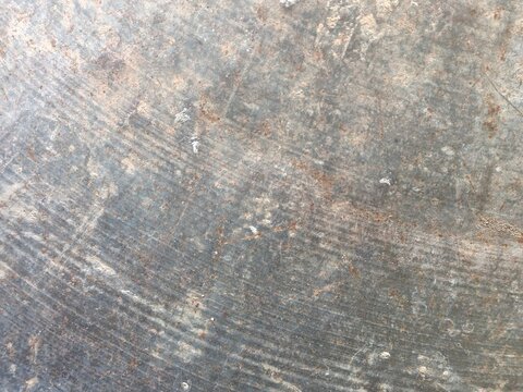 Macro texture of a weathered metal surface with fine circular grooves, scratches, dark oxidized patina, and subtle rust specks