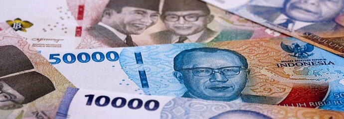 Indonesian rupiah money bills pile on table. Indonesia banknotes of IDR currency close up. © Larysa
