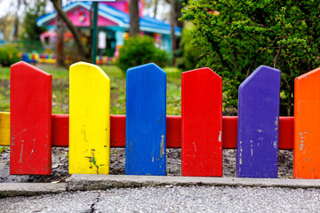 Obraz premium Bright multicolored wooden picket fence on a playground in a park, selective focus.
