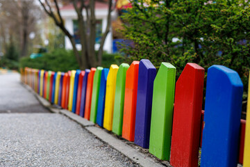 Obraz premium Bright multicolored wooden picket fence on a playground in a park, selective focus.