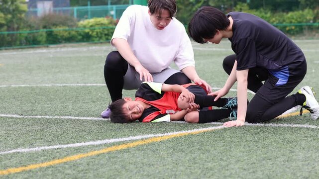 負傷した少年サッカー選手をケアするコーチ