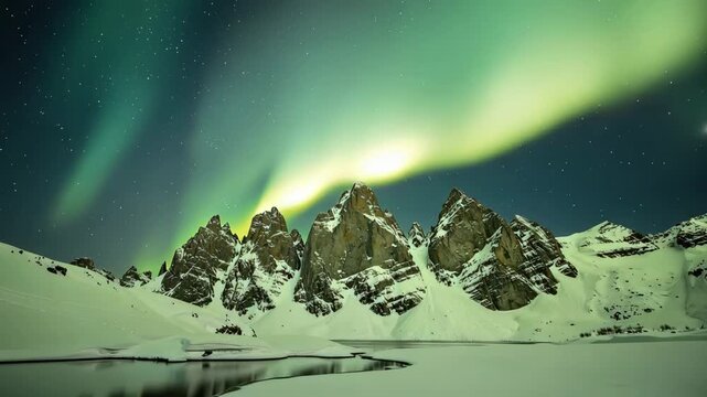 Aurora borealis dancing over majestic snow capped mountains with stunning reflections in icy waters at night