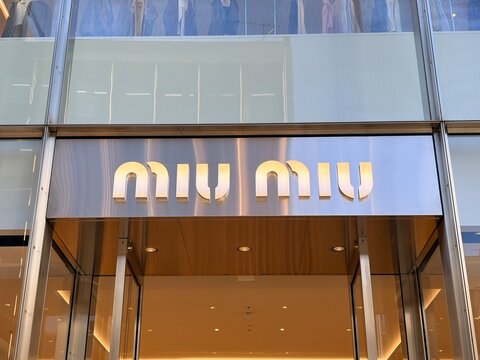 Miu Miu luxury fashion brand signage on a modern brushed metal and glass storefront exterior in the Ginza Chuo shopping district - Osaka, Japan, December 25, 2025