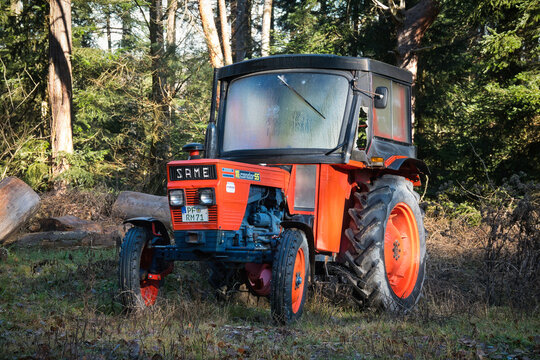 Ein alter, orangefarbener Traktor Marke Same Modell Condor 55 geparkt in einem Wald