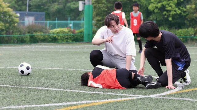 負傷した少年サッカー選手をケアするコーチ