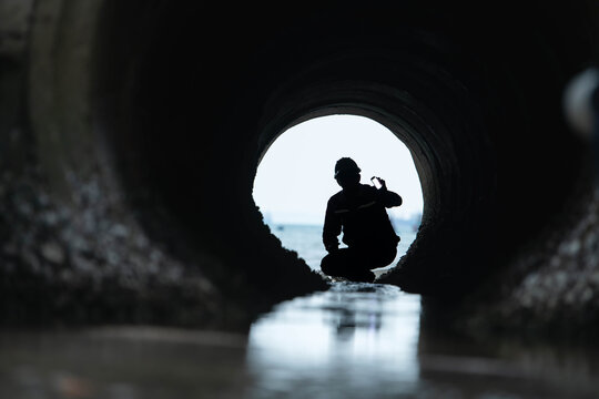 Silhouette of worker inspecting contaminated drainage tunnel
