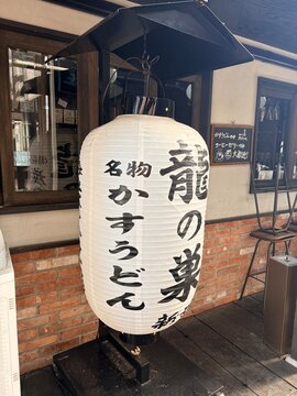 Traditional Japanese chochin lantern outside a restaurant at Okinawa Tourist office area in Minato district featuring calligraphy for kasu udon - Tokyo, Japan, December 25, 2025