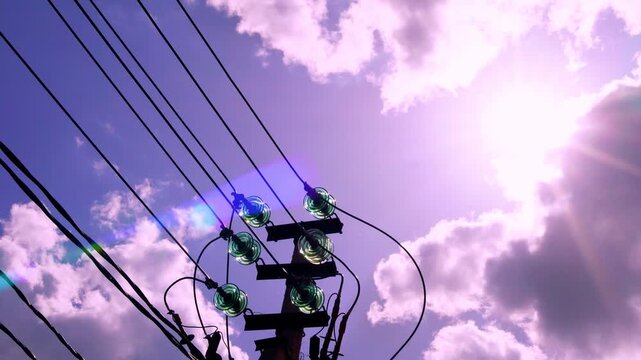 Electric grid tower and high-voltage wires, power line close-up, electricity, electric pole and beautiful sun sunlight sun rays sunbeams in sunset lilac blue sky colorful clouds time lapse.
