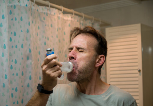 Man using asthma inhaler with spacer for respiratory relief