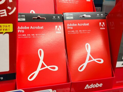 Adobe Acrobat Pro software retail subscription cards on display in a Japanese electronics store with red product packaging and company branding - Tokyo, Japan, December 22, 2025