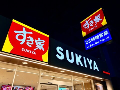 Sukiya gyudon restaurant exterior with illuminated red and yellow signage at night featuring 23-hour operation information and storefront lighting - Tokyo, Japan, December 20, 2025