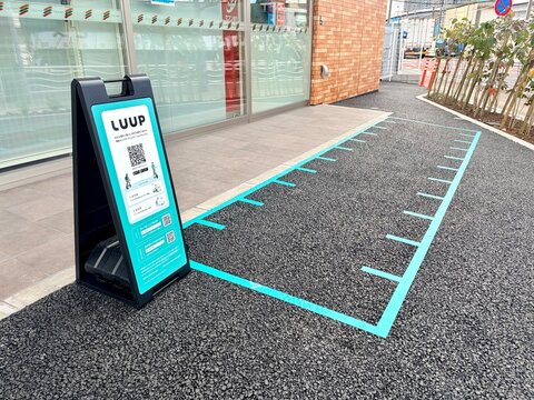 LUUP electric kickboard sharing port with marked parking spaces and digital signage outside a Seven-Eleven convenience store in Koto City - Tokyo, Japan, December 21, 2025