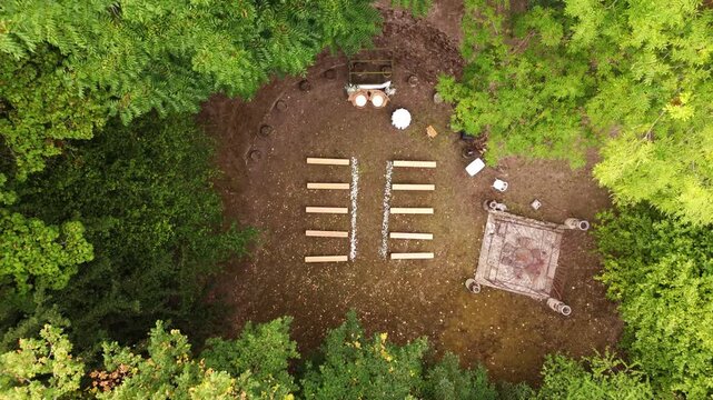 Outdoor forest wedding ceremony venue with benches, aerial top down view