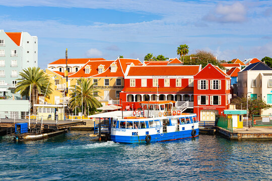 Willemctad, Curacao - 22.03.2026: Passenger ferry departing from the pier near colorful colonial buildings and restaurants at St Anna Bay in Curacao