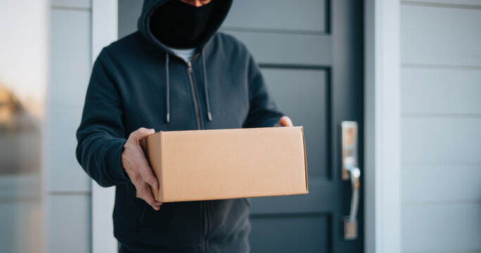Masked person delivering cardboard package