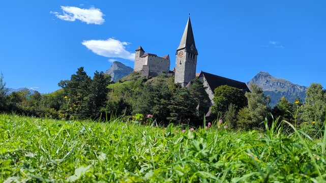 Medieval Gutenberg Castle and St Nicholas Church in Balzers Liechtenstein, historic alpine landmark under blue sky, ideal for European travel guides.