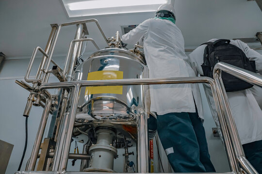 Male work inspection process stainless steel tanks and pipe with pressure meter in equipment tank facility for milk cellar at the with vertical stainless