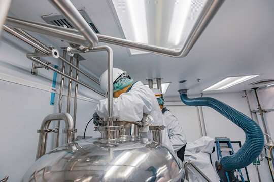 Male work inspection process stainless steel tanks and pipe with pressure meter in equipment tank facility for milk cellar at the with vertical stainless