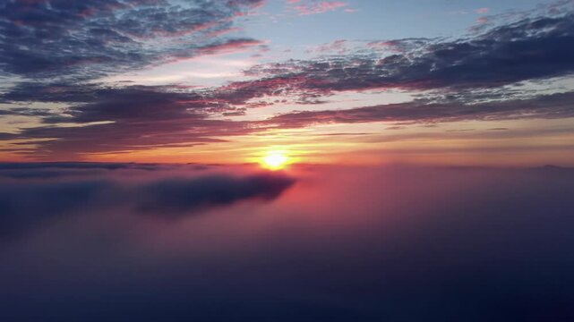 Wide establishing video pans left to right across vast sunrise/sunset sky, fiery oranges, molten golds, pinks, purples, blues, crepuscular rays. Concept of wonder and freedom