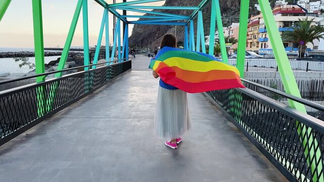 Gay pride parade, woman walking with rainbow lgbt flags