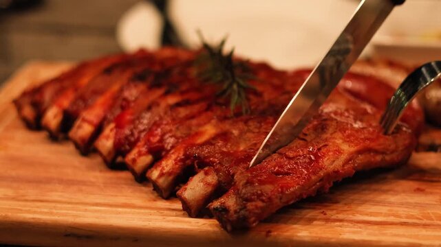 Cutting delicious grilled pork ribs with knife and fork on wooden board in cinematic restaurant setting.