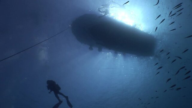 scuba diver scenery under the parked boats with sun beams and rays underwater