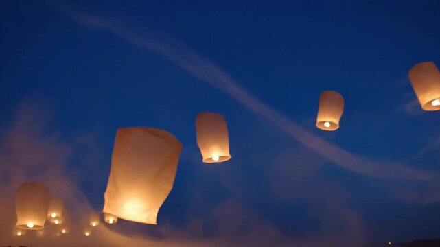 Lanterns flying high in the evening sky with people releasing lights