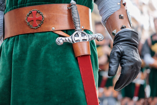 Detalle de espada medieval en el cintur&oacute;n de un guerrero con t&uacute;nica verde y guante de cuero, Alcoy, Espa&ntilde;a