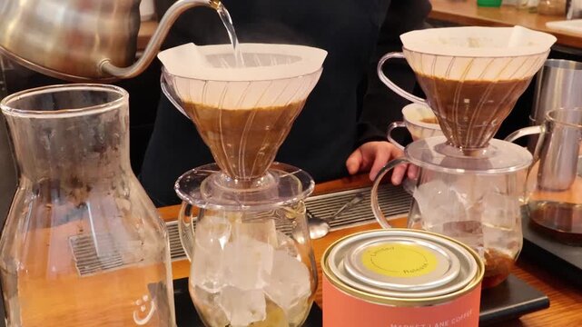 Pouring hot water over coffee grounds in a pour over dripper to make iced coffee.