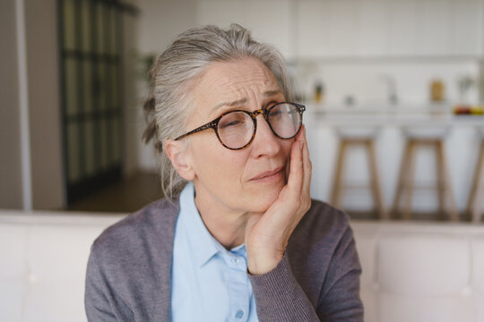 Elderly woman with tooth pain sitting at home, senior dental health issue, oral care problem, facial discomfort, healthcare, dentistry and pain relief concept