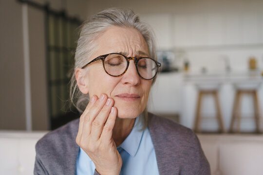 Senior woman suffering from toothache at home, elderly dental pain, oral health problem, healthcare concept, discomfort, sensitive teeth and medical care need