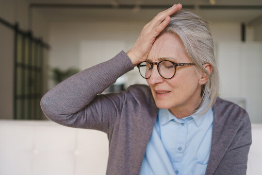 Elderly woman holding head because of headache at home, senior health issue, pain, tension, fatigue, discomfort, healthcare and recovery concept, close up