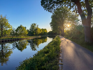 Obraz premium Peaceful canal towpath at golden hour sunset in Rijkevorsel, België with walking trail and water reflections
