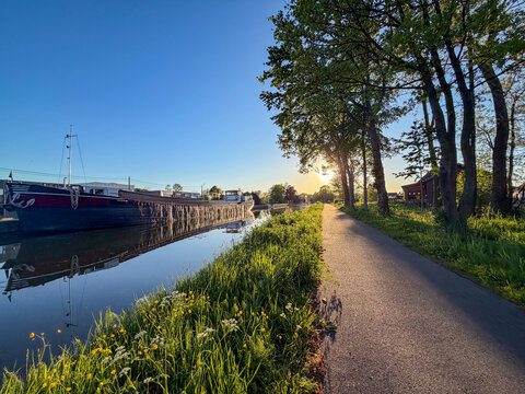 Peaceful canal towpath at sunset in Rijkevorsel, Belgi&euml; with moored barge and walking trail