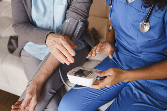 Close up of nurse measuring blood pressure of senior woman at home, healthcare monitoring, medical checkup, hypertension control, caregiver support, elderly care and home care concept