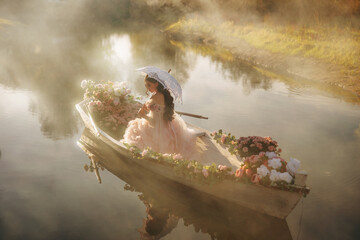 fantasy woman princess sitting in boat full of flowers white pink color floating down river fog nature. Fairy tale fashion model lady holding vintage lace umbrella, art victorian style dress back view © kharchenkoirina