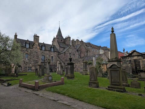 Edinburgh, UK - 13 April 2025. View of Canongate Kirk and its kirkyard in Edinburgh, showcasing the historic architecture and gravestones amidst lush greenery.